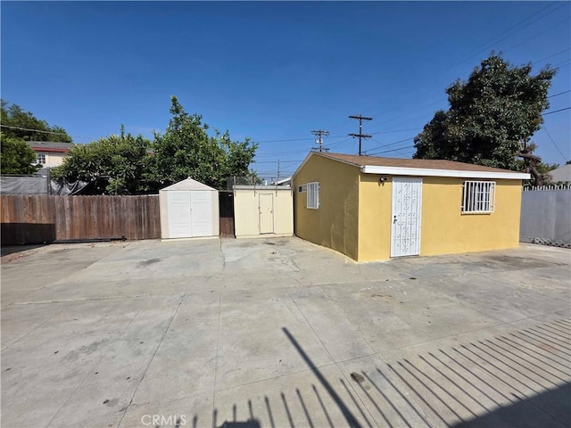 123 E Gage Ave, Los Angeles, CA 90003 - view of property exterior with stucco siding, a storage shed, and a patio area