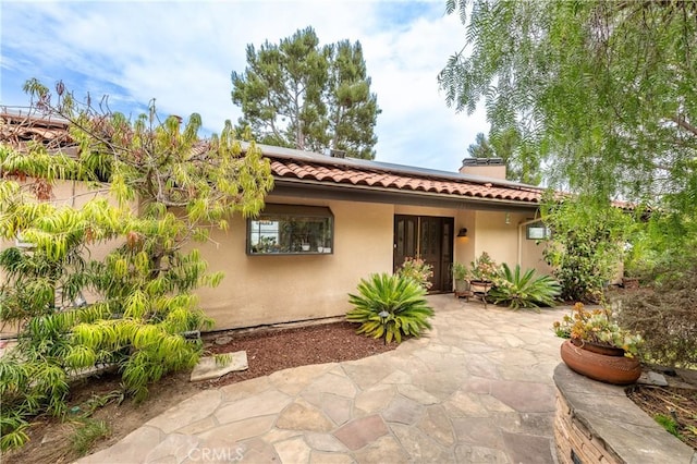 1960 Polaris Dr, Glendale, CA 91208 - view of front of house with a tiled roof, stucco siding, solar panels, and a patio area