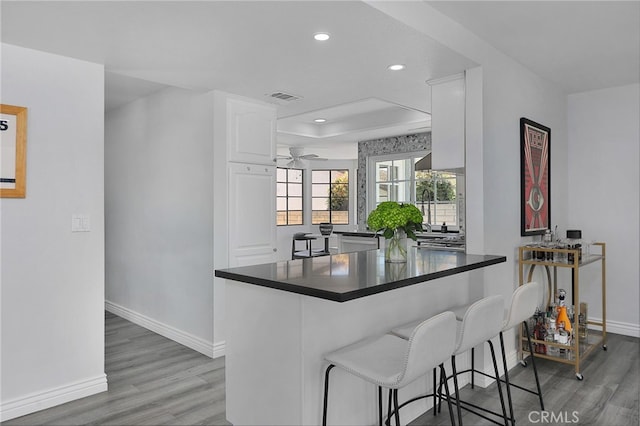 2861 Hillman St, Thousand Oaks, CA 91360 - kitchen featuring dark countertops, light wood-style flooring, recessed lighting, white cabinets, and a raised ceiling