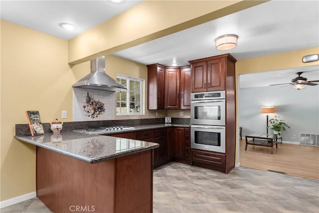 644 E Mountain View Ave, Glendora, CA 91741 - kitchen featuring wall chimney exhaust hood, appliances with stainless steel finishes, a peninsula, dark stone countertops, and a ceiling fan
