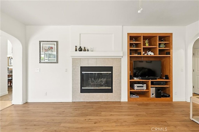 9790 Heatherhearst Dr, Chowchilla, CA 93610 - unfurnished living room featuring arched walkways, wood finished floors, and a tile fireplace