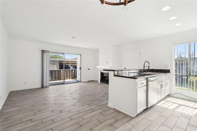 2827 S Fairview St Unit O, Santa Ana, CA 92704 - kitchen featuring dishwasher, white cabinetry, a peninsula, dark countertops, and light wood-type flooring