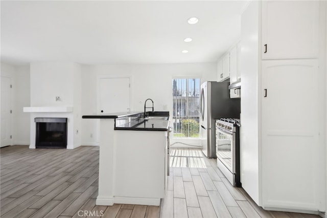 2827 S Fairview St Unit O, Santa Ana, CA 92704 - kitchen featuring stainless steel range with gas stovetop, light wood-style floors, under cabinet range hood, white cabinetry, and recessed lighting