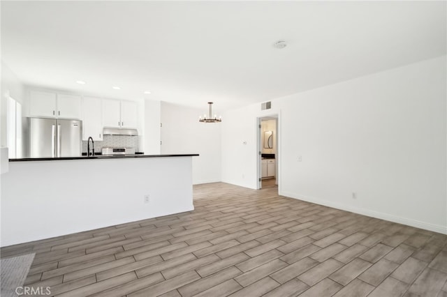 2827 S Fairview St Unit O, Santa Ana, CA 92704 - kitchen featuring stainless steel refrigerator, dark countertops, a chandelier, decorative backsplash, and under cabinet range hood