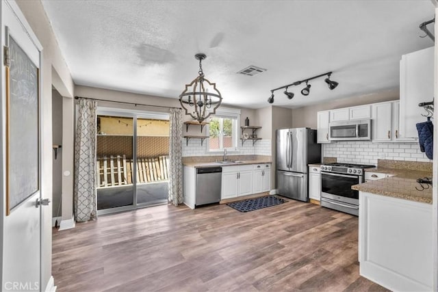5616 Cahuilla Ave Unit 29, Palms, CA 92277 - kitchen with appliances with stainless steel finishes, white cabinets, tasteful backsplash, a chandelier, and decorative light fixtures