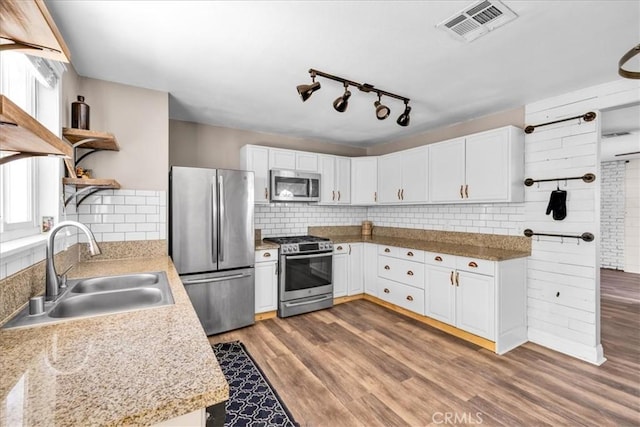 5616 Cahuilla Ave Unit 29, Palms, CA 92277 - kitchen with appliances with stainless steel finishes, open shelves, tasteful backsplash, and white cabinets