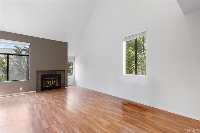 2224 River Run Dr Unit 154, San Diego, CA 92108 - unfurnished living room featuring healthy amount of natural light, light wood-type flooring, high vaulted ceiling, and a brick fireplace