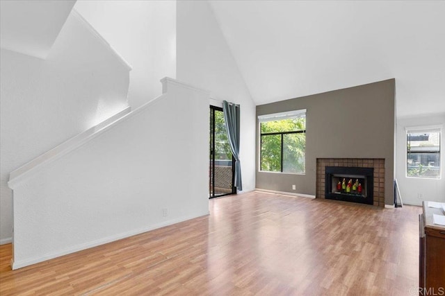 2224 River Run Dr Unit 154, San Diego, CA 92108 - unfurnished living room with high vaulted ceiling, light wood-style flooring, a fireplace, and stairs