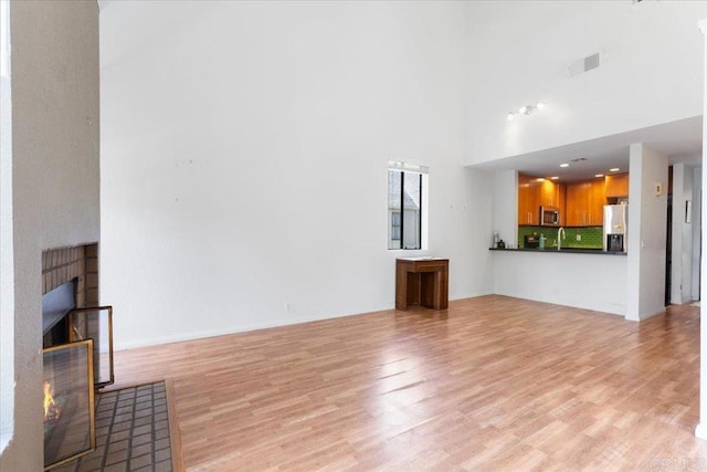 2224 River Run Dr Unit 154, San Diego, CA 92108 - unfurnished living room featuring light wood-style flooring and a towering ceiling