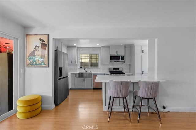 17172 Lahey St, Granada Hills, CA 91344 - kitchen with appliances with stainless steel finishes, a kitchen bar, light wood-style floors, backsplash, and light countertops