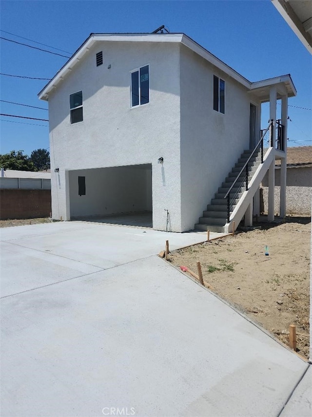 10531 Alexander Ave, South Gate, CA 90280 - view of side of property featuring an attached garage, stairs, stucco siding, and concrete driveway