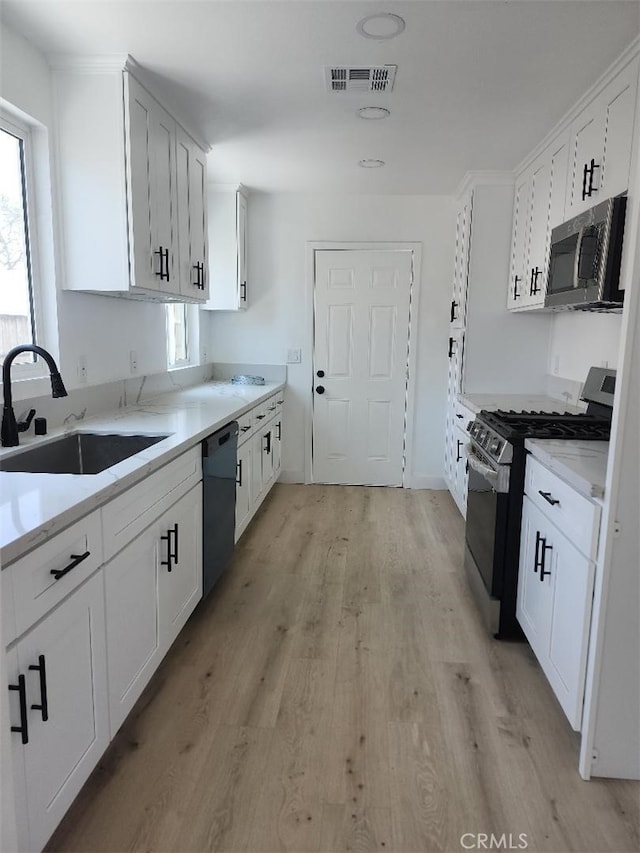 10531 Alexander Ave, South Gate, CA 90280 - kitchen featuring stainless steel appliances, light wood-type flooring, white cabinets, and light stone countertops