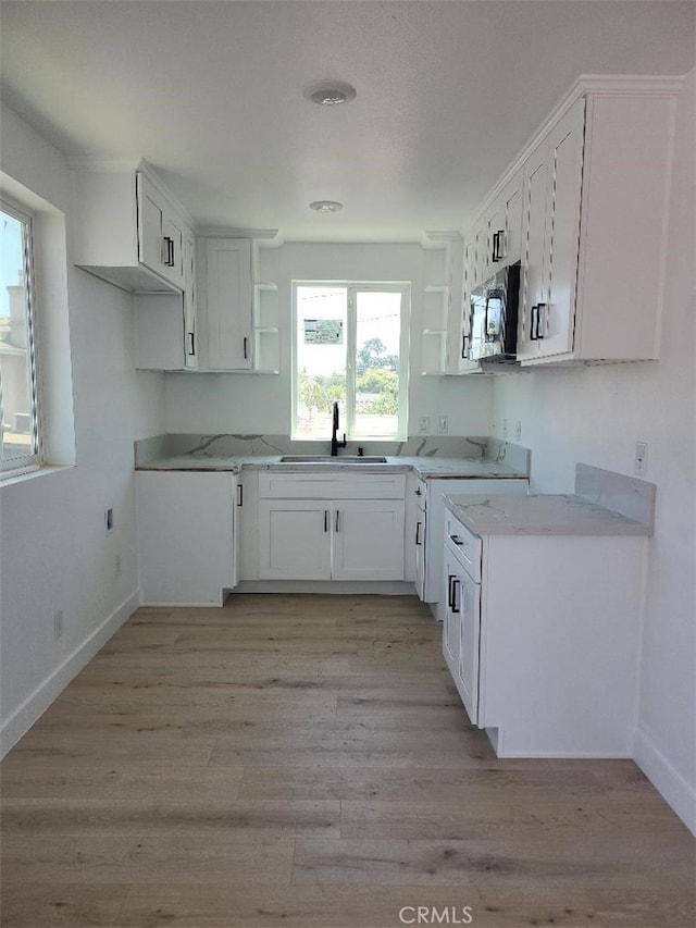 10531 Alexander Ave, South Gate, CA 90280 - kitchen with open shelves, stainless steel microwave, light wood-style flooring, and white cabinets