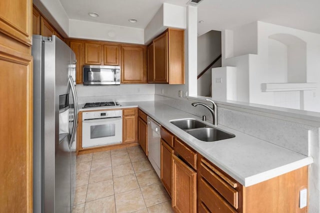 6410 Terraza Portico, Carlsbad, CA 92009 - kitchen featuring stainless steel appliances, light countertops, light tile patterned floors, brown cabinetry, and recessed lighting
