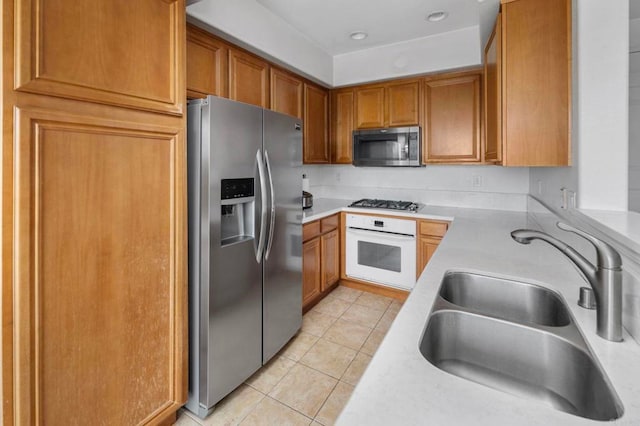 6410 Terraza Portico, Carlsbad, CA 92009 - kitchen with stainless steel appliances, light tile patterned floors, light countertops, and brown cabinets