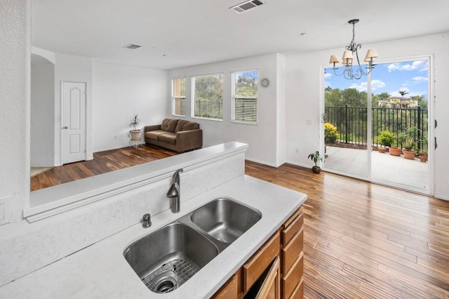 6410 Terraza Portico, Carlsbad, CA 92009 - kitchen featuring brown cabinets, light countertops, a chandelier, wood finished floors, and plenty of natural light