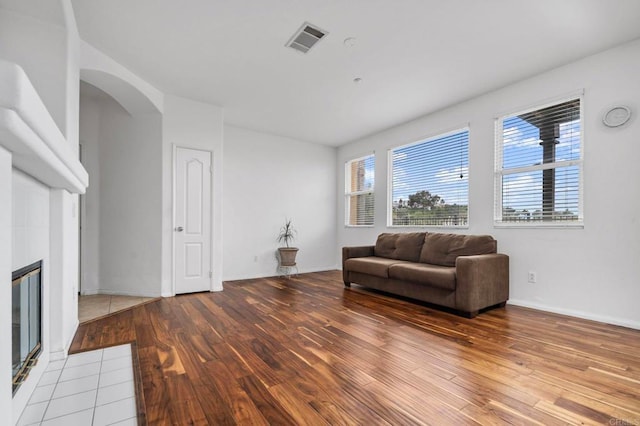 6410 Terraza Portico, Carlsbad, CA 92009 - sitting room with wood-type flooring, a tiled fireplace, and arched walkways
