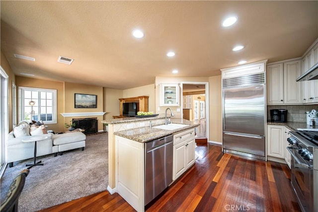 5620 La Paz St, Long Beach, CA 90803 - kitchen featuring high end appliances, a fireplace, open floor plan, dark wood-style floors, and light stone countertops