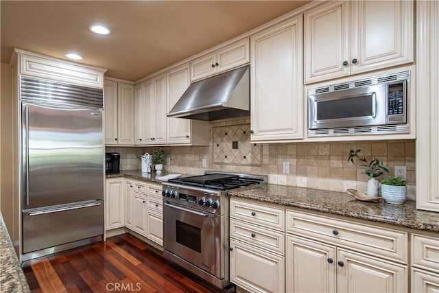 5620 La Paz St, Long Beach, CA 90803 - kitchen with built in appliances, under cabinet range hood, dark wood-style floors, tasteful backsplash, and dark stone counters