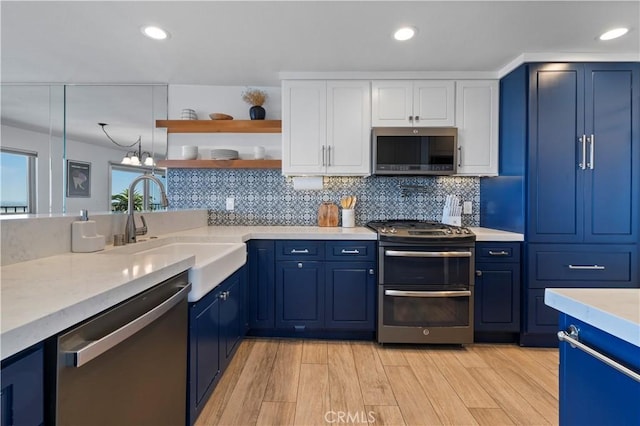2700 E Panorama Dr Unit 208, Signal Hill, CA 90755 - kitchen with appliances with stainless steel finishes, blue cabinets, white cabinets, light wood-type flooring, and backsplash