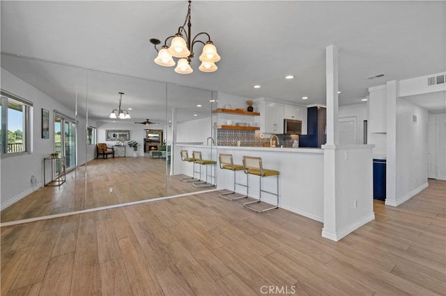 2700 E Panorama Dr Unit 208, Signal Hill, CA 90755 - kitchen featuring a chandelier, open shelves, light wood-style flooring, a breakfast bar, and white cabinetry