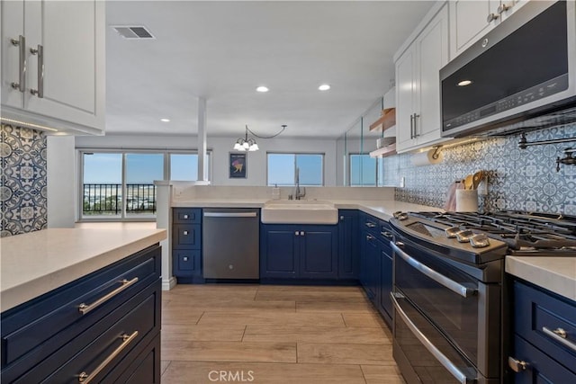 2700 E Panorama Dr Unit 208, Signal Hill, CA 90755 - kitchen featuring appliances with stainless steel finishes, blue cabinetry, white cabinets, light countertops, and decorative backsplash