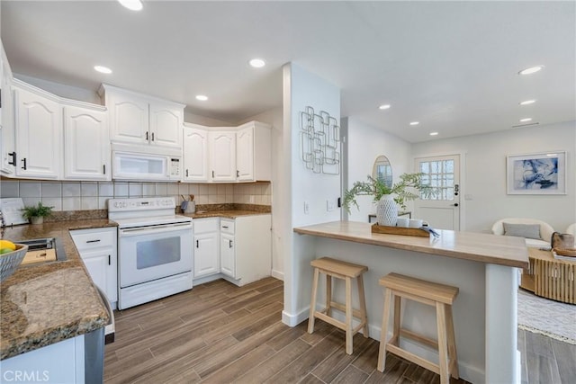 2302 Cayuga Ave, Placentia, CA 92870 - kitchen featuring white appliances, wood finished floors, a breakfast bar, white cabinetry, and recessed lighting