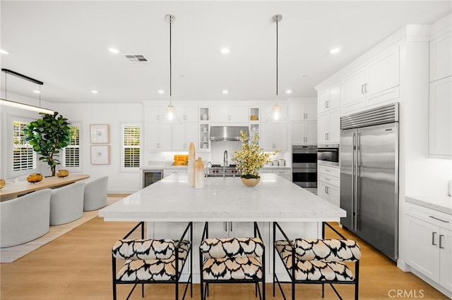 56 Cartwheel, Irvine, CA 92618 - kitchen with stainless steel appliances, beverage cooler, white cabinetry, under cabinet range hood, and a kitchen breakfast bar