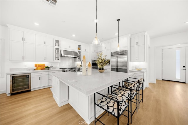 56 Cartwheel, Irvine, CA 92618 - kitchen featuring beverage cooler, range hood, light wood-style flooring, white cabinets, and recessed lighting