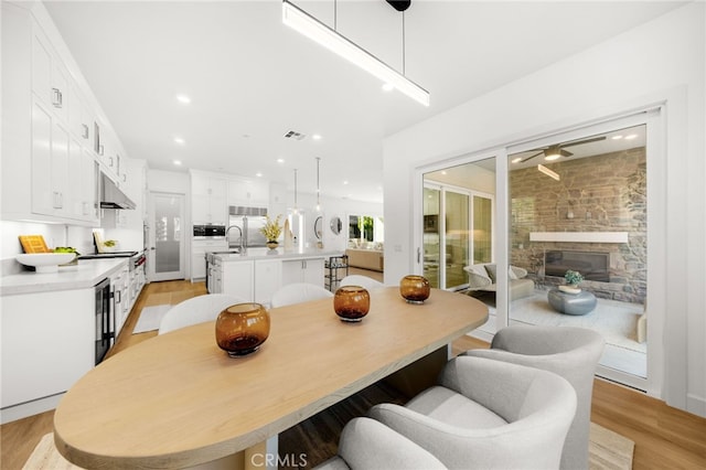 56 Cartwheel, Irvine, CA 92618 - dining space with a ceiling fan, light wood finished floors, recessed lighting, and a stone fireplace