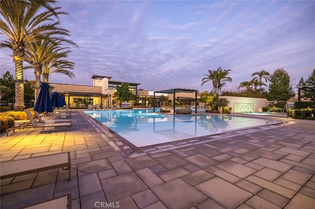 56 Cartwheel, Irvine, CA 92618 - pool at dusk featuring a pergola, a patio area, and a community pool