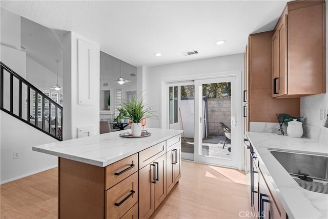 2 Chestnut Dr, Aliso Viejo, CA 92656 - kitchen with light wood-style flooring, ceiling fan, light stone countertops, brown cabinets, and recessed lighting