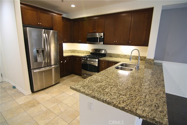 629 Traction Ave Unit 508, Los Angeles, CA 90013 - kitchen with stainless steel appliances, a peninsula, light stone counters, wainscoting, and dark brown cabinetry