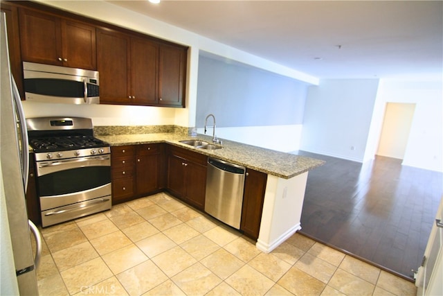629 Traction Ave Unit 508, Los Angeles, CA 90013 - kitchen with appliances with stainless steel finishes, a peninsula, light stone countertops, dark brown cabinetry, and light tile patterned floors