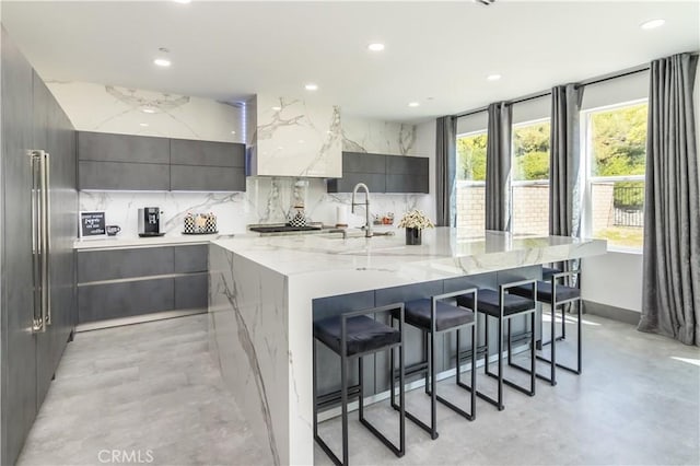 18824 Juniper Springs Dr, Canyon Country, CA 91321 - kitchen with modern cabinets, a large island with sink, recessed lighting, a breakfast bar, and decorative backsplash