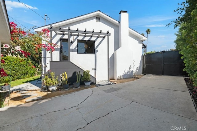 2329 Vineyard Ave, Los Angeles, CA 90016 - view of side of home featuring a chimney, stucco siding, and a gate