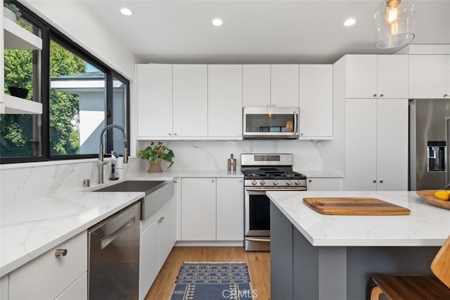 2329 Vineyard Ave, Los Angeles, CA 90016 - kitchen with stainless steel appliances, light wood-style floors, recessed lighting, white cabinets, and tasteful backsplash