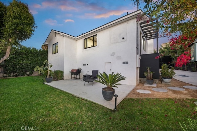2329 Vineyard Ave, Los Angeles, CA 90016 - back of house at dusk featuring stucco siding, a lawn, and a patio area