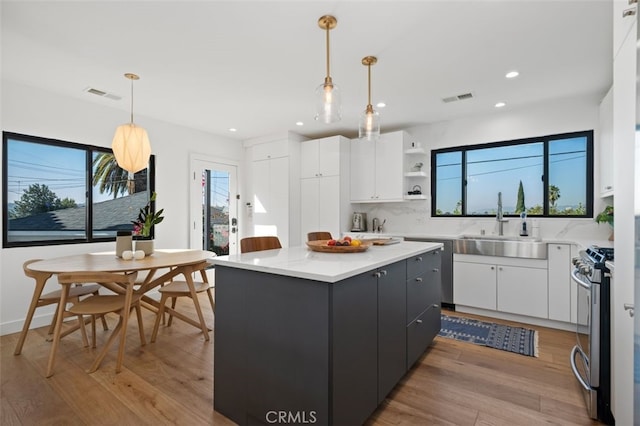 2329 Vineyard Ave, Los Angeles, CA 90016 - kitchen with stainless steel gas range, white cabinetry, a kitchen island, recessed lighting, and light wood finished floors