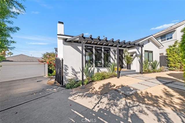 2329 Vineyard Ave, Los Angeles, CA 90016 - view of front facade featuring a pergola, stucco siding, an outbuilding, a detached garage, and a chimney