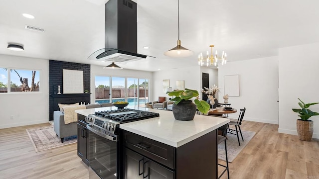 8865 Highsmith Ln, San Diego, CA 92119 - kitchen featuring stainless steel range with gas stovetop, island range hood, a breakfast bar, open floor plan, and light wood finished floors