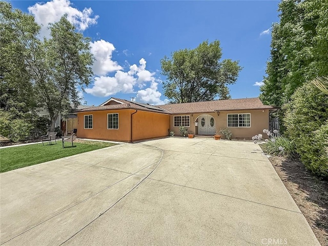 24017 Sylvan St, Woodland Hills, CA 91367 - ranch-style home with stucco siding, a front yard, roof mounted solar panels, and driveway