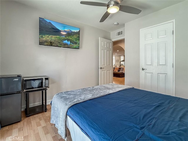 24017 Sylvan St, Woodland Hills, CA 91367 - bedroom with freestanding refrigerator, arched walkways, light wood-style floors, and a ceiling fan