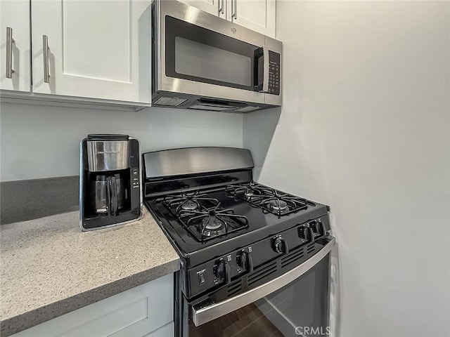 24017 Sylvan St, Woodland Hills, CA 91367 - kitchen featuring stainless steel microwave, black gas range oven, and white cabinets