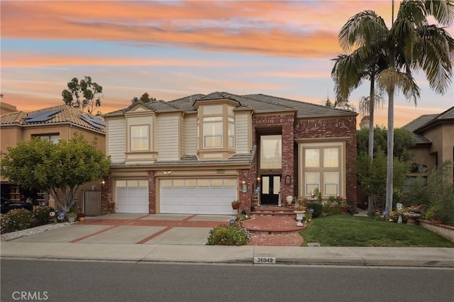 26942 Willow Tree Ln, Laguna Hills, CA 92653 - view of front of property featuring driveway, an attached garage, brick siding, a lawn, and a tile roof