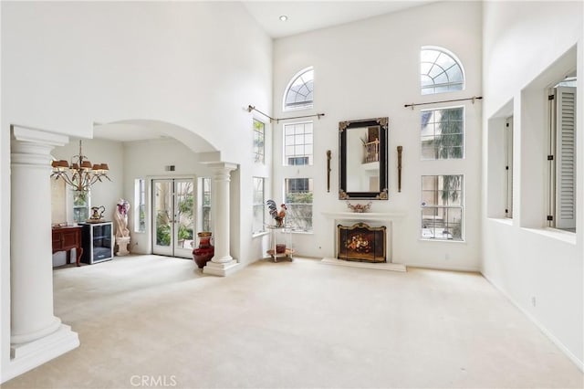 26942 Willow Tree Ln, Laguna Hills, CA 92653 - unfurnished living room with a high ceiling, carpet floors, arched walkways, decorative columns, and healthy amount of natural light