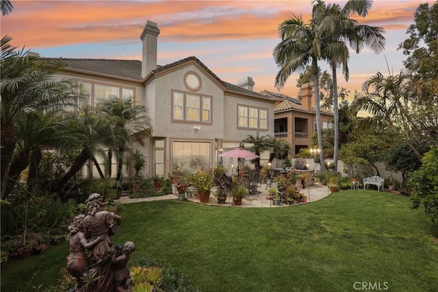 26942 Willow Tree Ln, Laguna Hills, CA 92653 - rear view of house featuring a chimney, a patio, a lawn, stucco siding, and a tiled roof