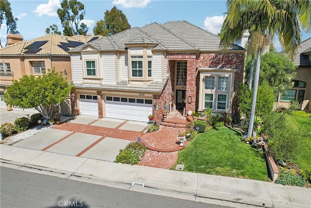 26942 Willow Tree Ln, Laguna Hills, CA 92653 - view of front of house featuring driveway, an attached garage, brick siding, a front yard, and a tile roof