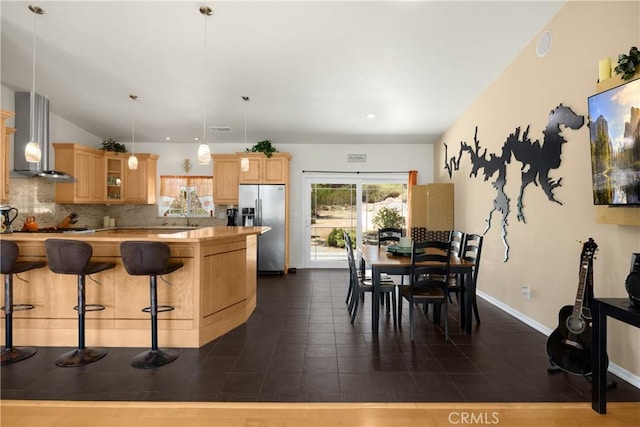 4766 Egret Ln, Paso Robles, CA 93446 - kitchen with stainless steel fridge, wall chimney exhaust hood, tasteful backsplash, light brown cabinets, and a kitchen breakfast bar