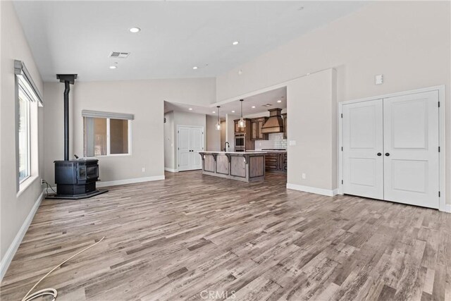 21813 Valley Vista Dr, Tehachapi, CA 93561 - unfurnished living room featuring a wood stove, light wood finished floors, high vaulted ceiling, and recessed lighting